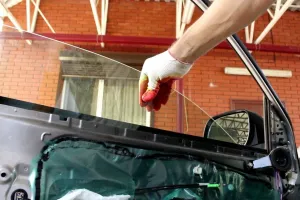 Technician lowering a new door glass into a car door
