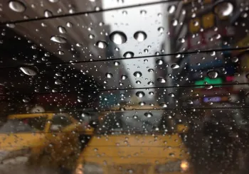 Raindrops on a car window with traffic behind