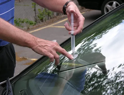 Technician injecting resin into a windshield chip