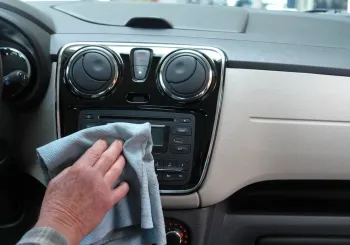 Wiping down a car dashboard below the windshield